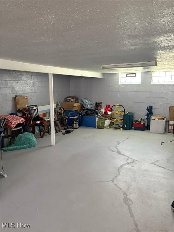basement featuring concrete block wall and a textured ceiling
