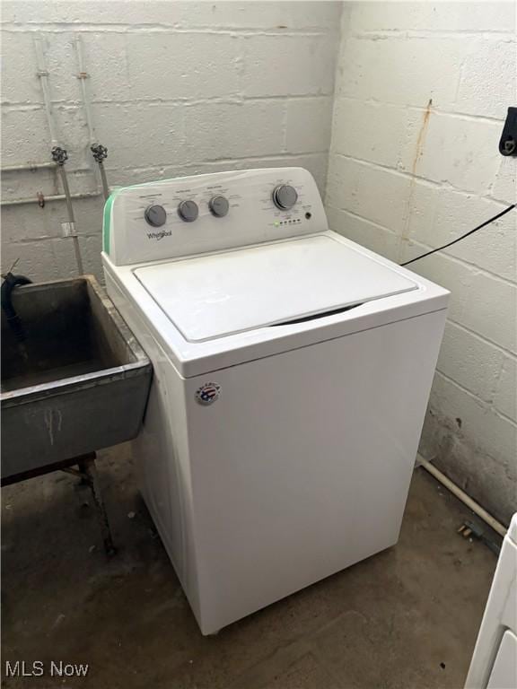 washroom featuring laundry area, a sink, washer / clothes dryer, and concrete block wall