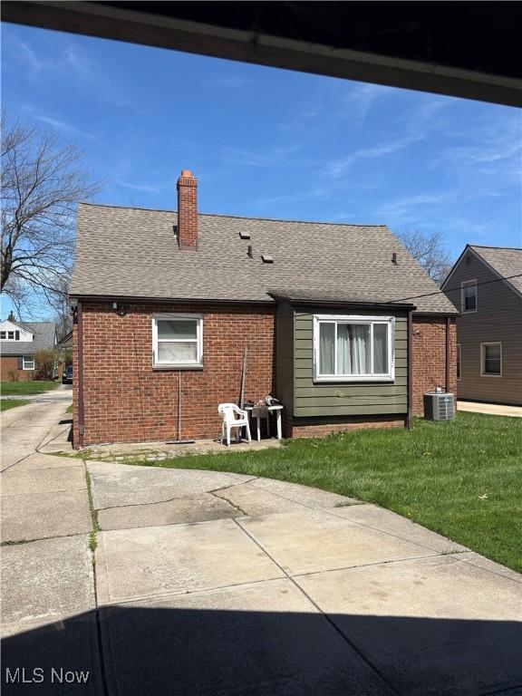 back of property featuring a chimney, a yard, and brick siding