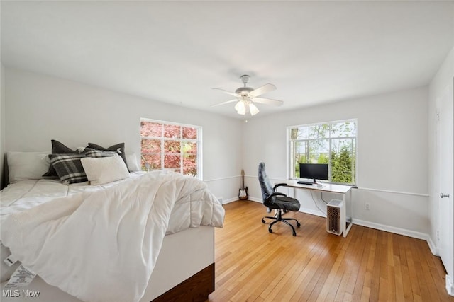bedroom with baseboards, multiple windows, and light wood-style flooring