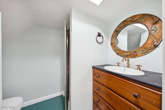 bathroom featuring toilet, baseboards, vaulted ceiling, and vanity