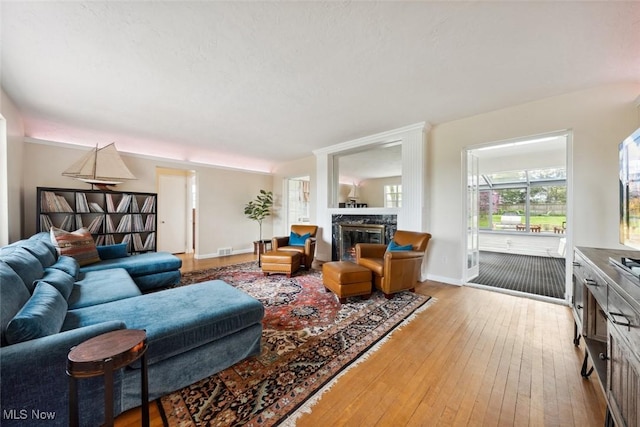 living area with visible vents, baseboards, a premium fireplace, and hardwood / wood-style flooring