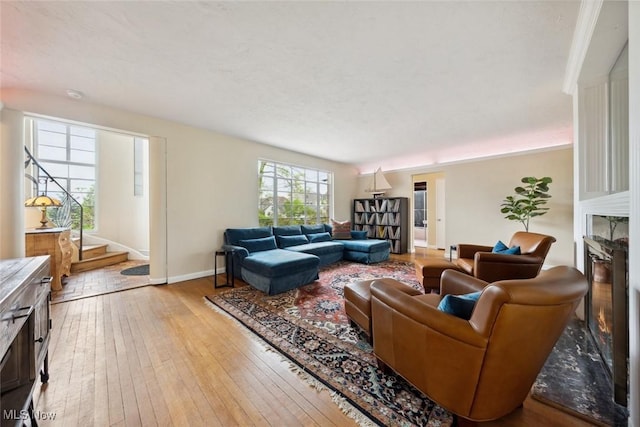 living room with baseboards, light wood finished floors, and a glass covered fireplace