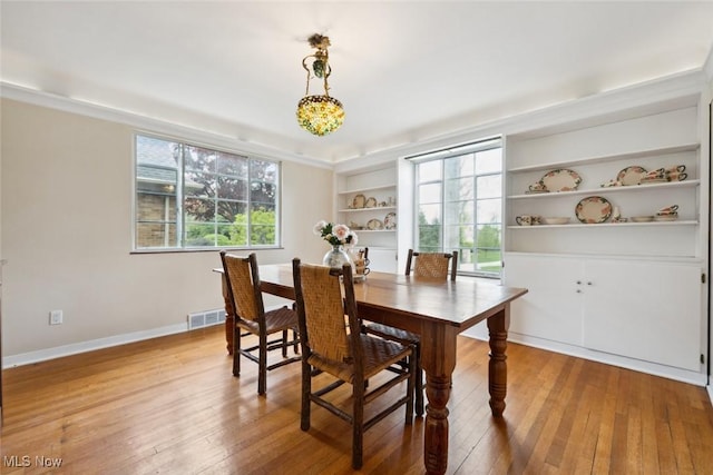 dining space with baseboards, visible vents, built in features, and hardwood / wood-style floors