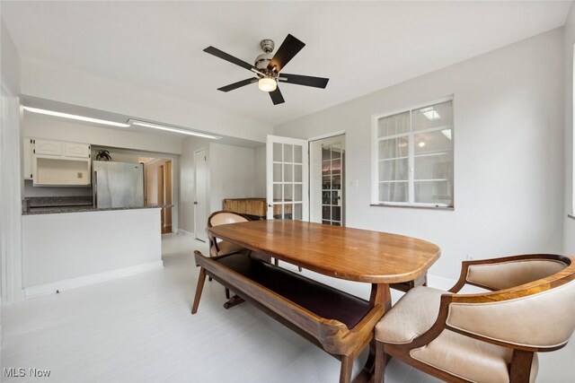 dining area featuring a ceiling fan, baseboards, and light floors