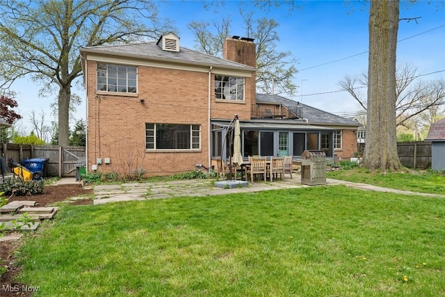 rear view of property featuring a lawn, brick siding, a chimney, and a fenced backyard