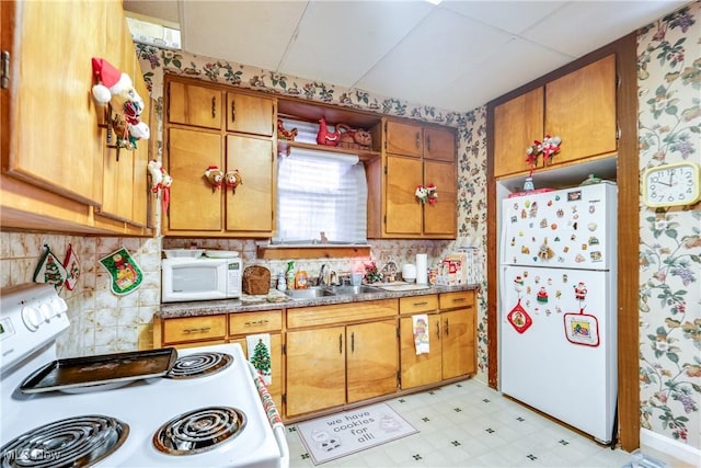 kitchen featuring a sink, light floors, brown cabinets, and white appliances