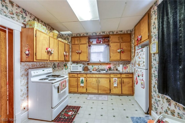 kitchen with white appliances, brown cabinets, a paneled ceiling, and light floors