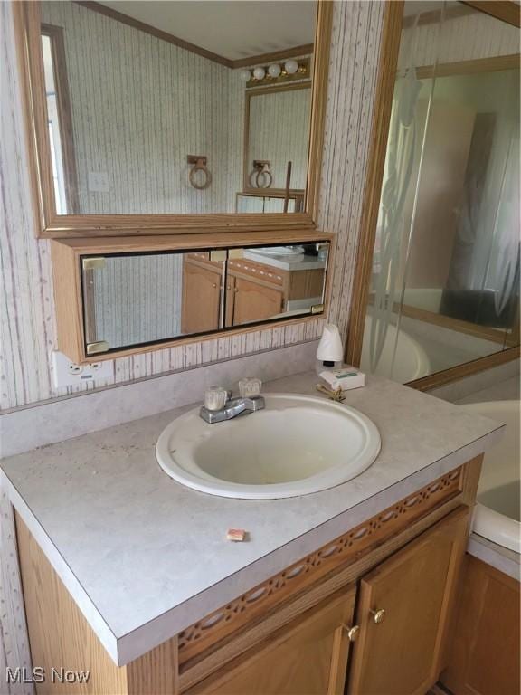 full bath featuring a tub, ornamental molding, and vanity