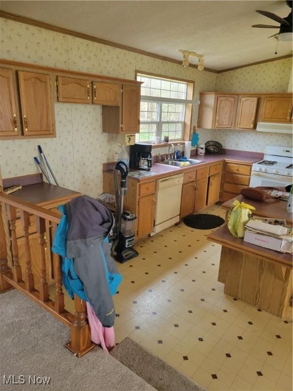 kitchen with a sink, ornamental molding, white appliances, and wallpapered walls