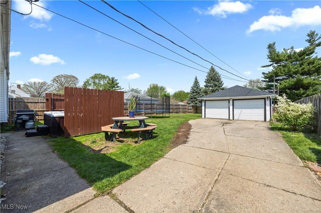 view of yard with a garage, a trampoline, fence, and an outbuilding