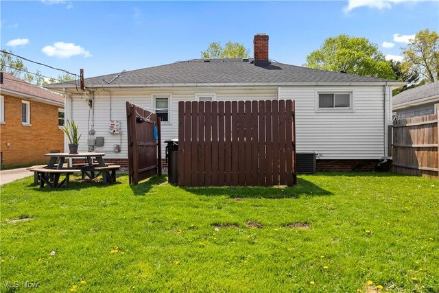 back of property with a yard, fence, a chimney, and cooling unit