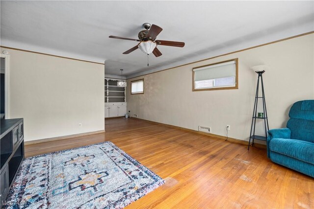 unfurnished room with visible vents, ornamental molding, wood finished floors, baseboards, and a ceiling fan