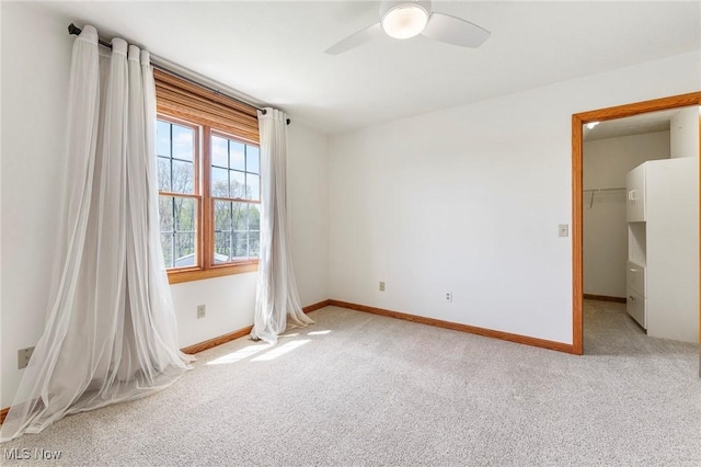 unfurnished bedroom featuring baseboards, ceiling fan, light carpet, and a spacious closet