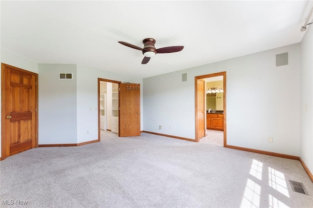 unfurnished bedroom featuring baseboards, light carpet, and visible vents
