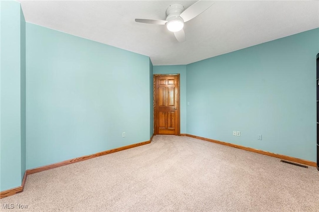 carpeted spare room featuring baseboards, a ceiling fan, and visible vents