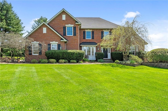 view of front facade with brick siding and a front yard