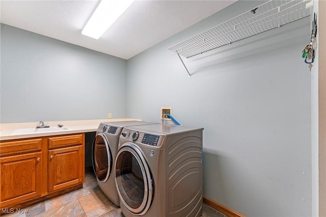 laundry room with a sink, stone finish flooring, cabinet space, and washer and dryer