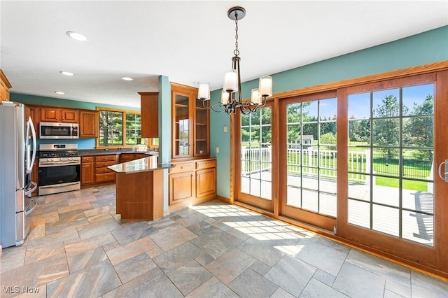 kitchen featuring stone tile floors, appliances with stainless steel finishes, a notable chandelier, and brown cabinets