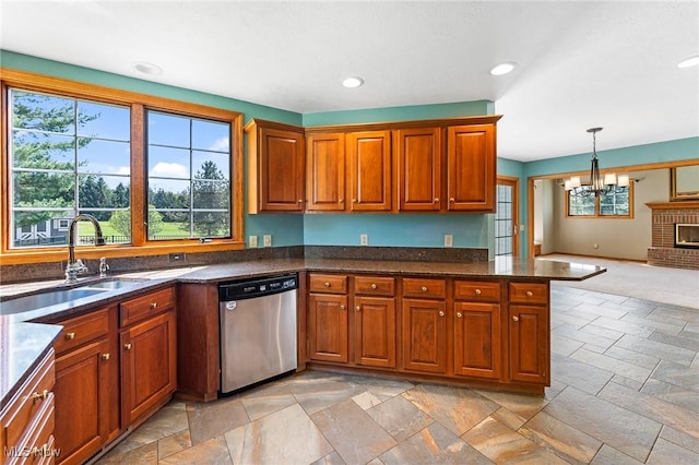 kitchen with brown cabinetry, dishwasher, a sink, a chandelier, and stone tile floors