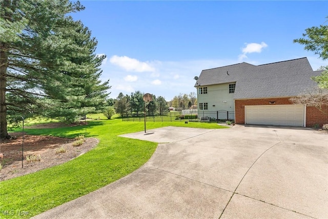 view of side of home featuring a garage, fence, brick siding, a lawn, and driveway