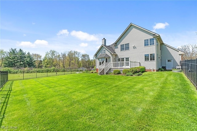 rear view of property featuring a fenced backyard, a yard, a chimney, and a deck