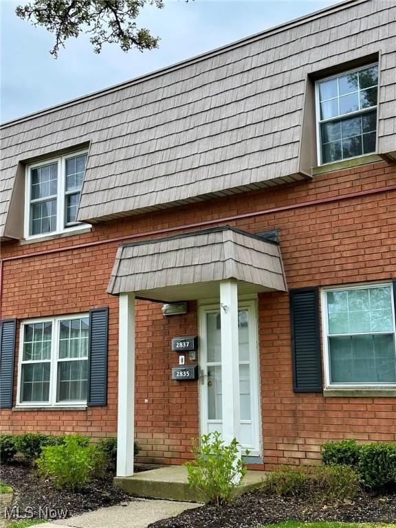 doorway to property with mansard roof and brick siding