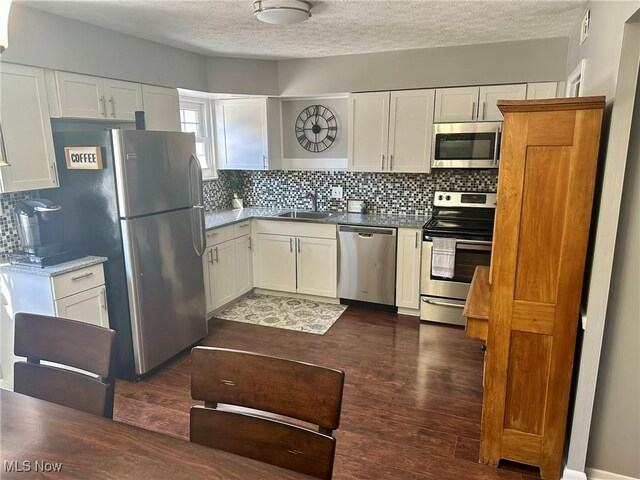 kitchen with decorative backsplash, a textured ceiling, appliances with stainless steel finishes, a sink, and white cabinets