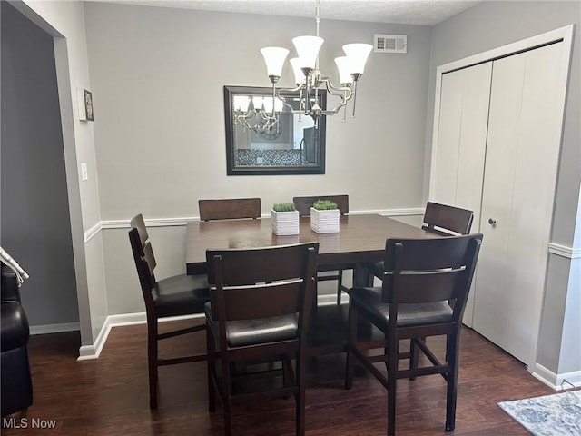 dining room with baseboards, a chandelier, wood finished floors, and visible vents
