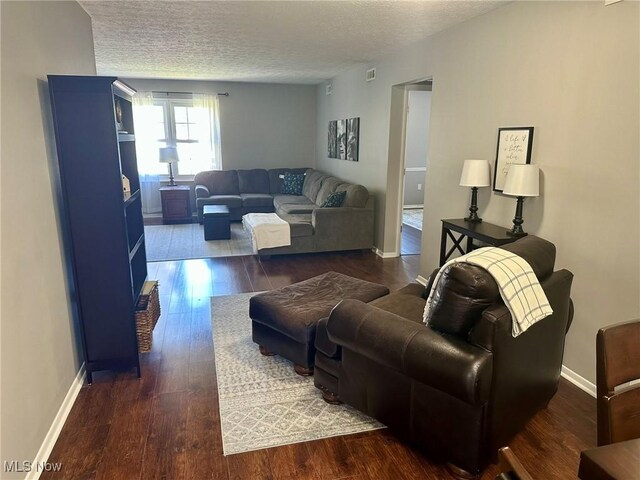 living room with baseboards, a textured ceiling, and dark wood finished floors