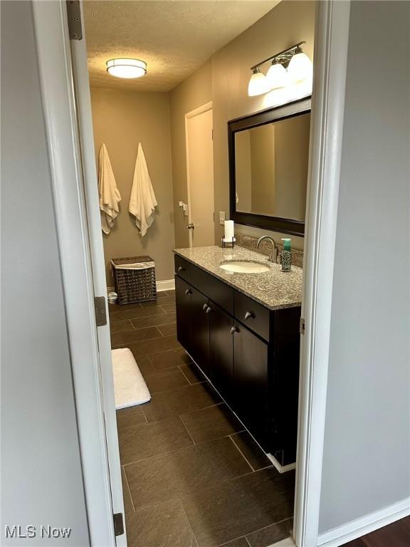 bathroom featuring vanity, a textured ceiling, and baseboards