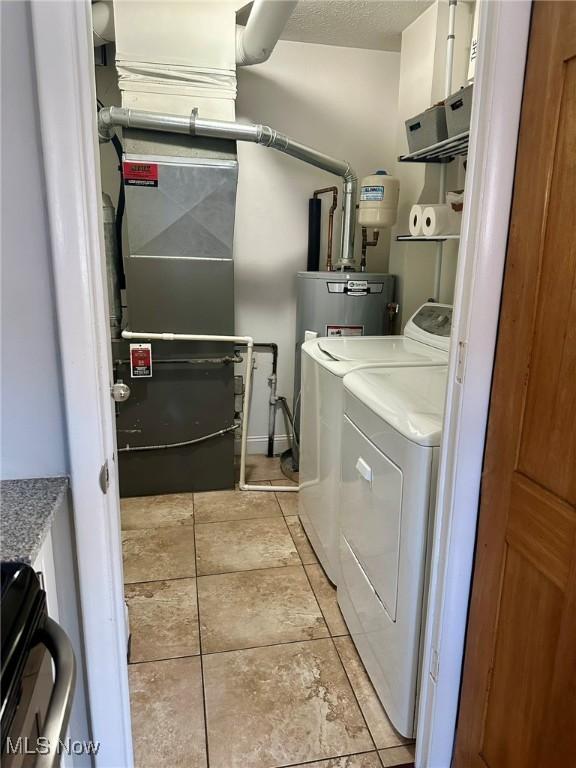 clothes washing area featuring laundry area, washing machine and dryer, and water heater