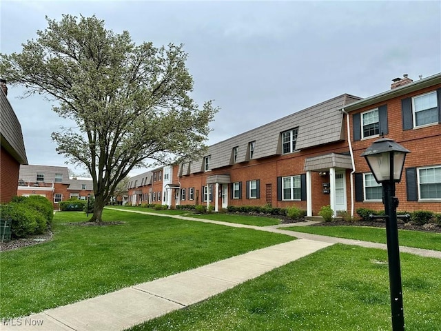 view of front of house featuring a residential view, a front lawn, and brick siding