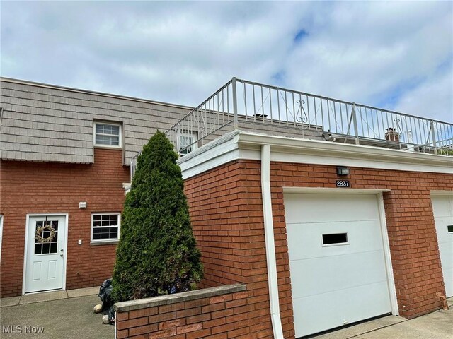 view of side of home featuring an attached garage, driveway, and brick siding