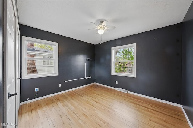 unfurnished room featuring ceiling fan, visible vents, baseboards, and hardwood / wood-style flooring