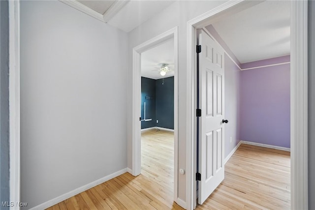 hall with baseboards, ornamental molding, and light wood-type flooring