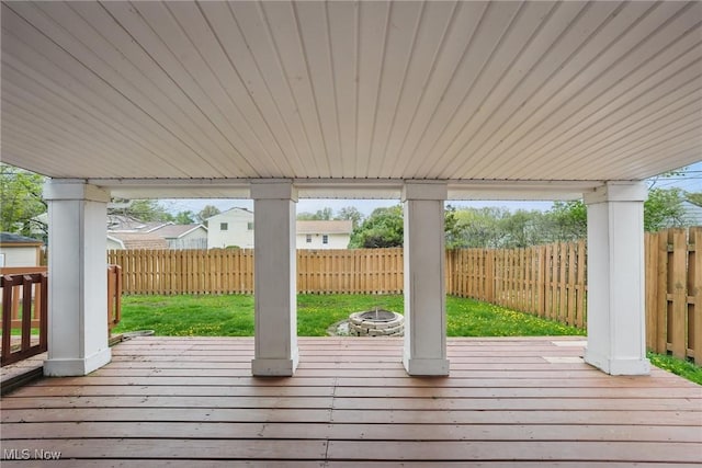 deck with a fenced backyard, a yard, and a fire pit