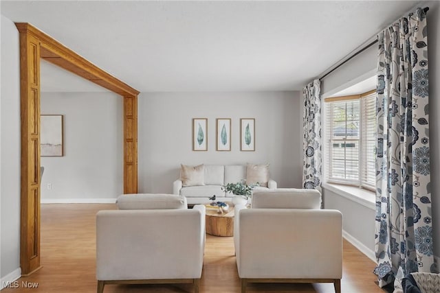living area featuring baseboards and light wood finished floors