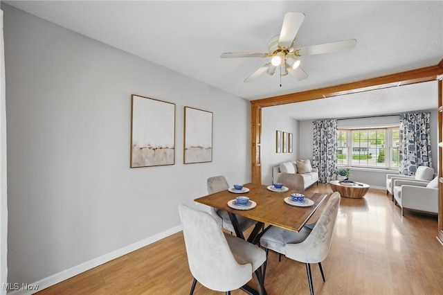 dining area featuring a ceiling fan, baseboards, and light wood-type flooring
