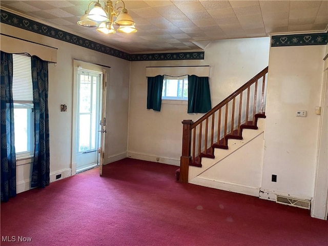 foyer with carpet flooring, an inviting chandelier, ornamental molding, and stairs