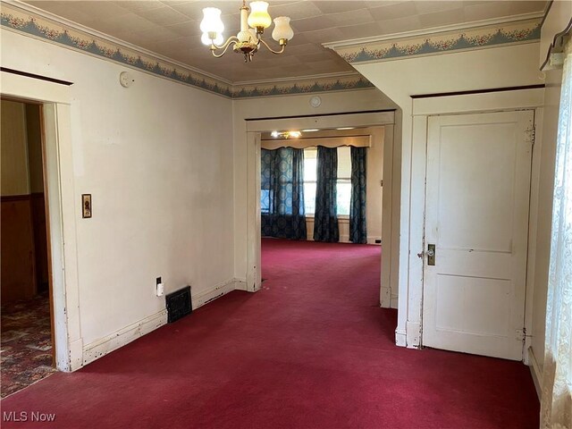 interior space featuring crown molding, baseboards, carpet, and a chandelier