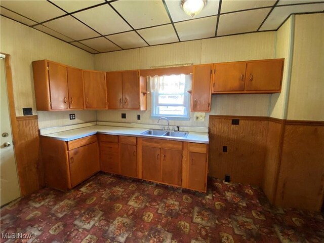 kitchen featuring light countertops, wooden walls, and a sink