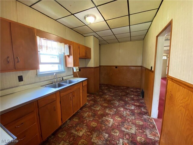 kitchen featuring brown cabinetry, a sink, and a wainscoted wall
