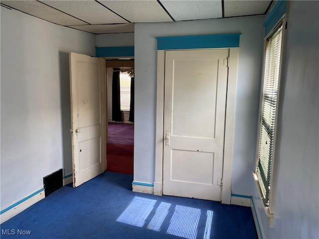 unfurnished bedroom with baseboards, carpet flooring, a paneled ceiling, and baseboard heating