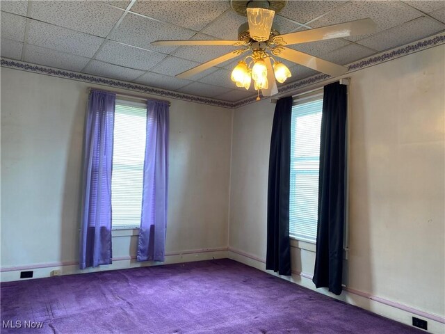 carpeted empty room with ceiling fan and a paneled ceiling