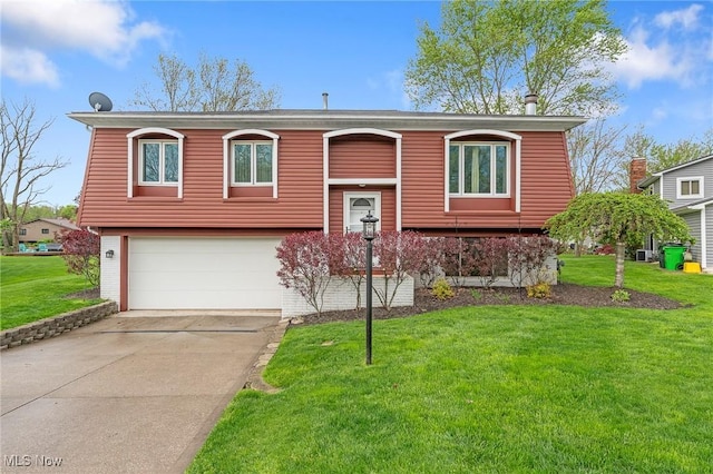 raised ranch featuring a garage, driveway, and a front lawn
