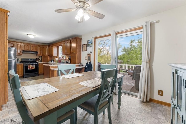 dining area with baseboards, stone tile floors, and a ceiling fan