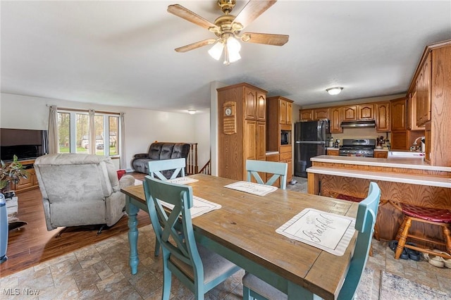 dining room with a ceiling fan and stone finish floor