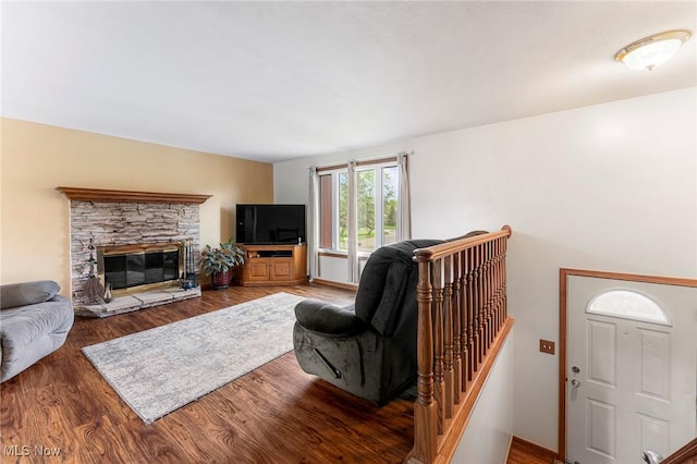 living area featuring a stone fireplace and wood finished floors