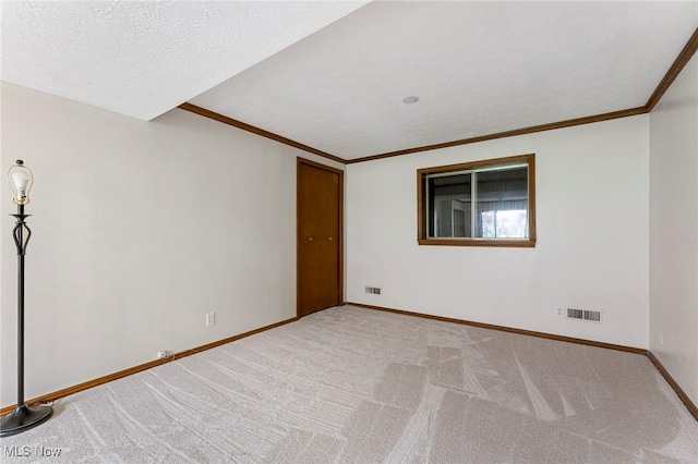 empty room with baseboards, ornamental molding, carpet, and visible vents